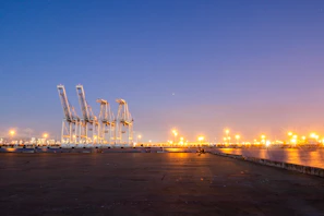 Evening view of the weightbridge illuminated by warm lights with trucks lined up, showcasing the busy activity.