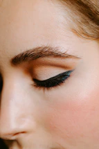 Close-up photo of a woman with perfectly shaped microbladed eyebrows, smiling gently.