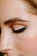 A close-up of a person's face focusing on the eye area, showcasing a perfectly shaped eyebrow and eye makeup with sleek black eyeliner and neutral eyeshadow.