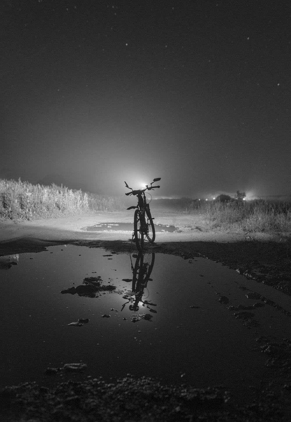 grayscale photo of man riding bicycle on snow covered ground