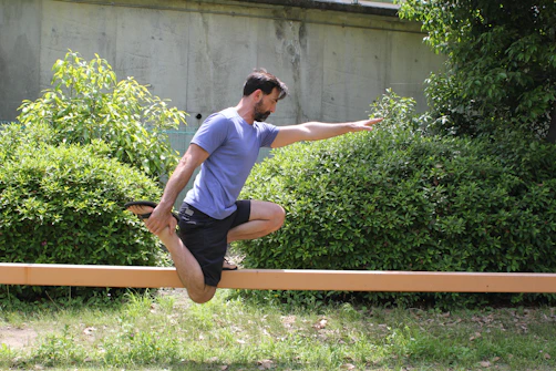 Man balancing on a wooden beam outdoors