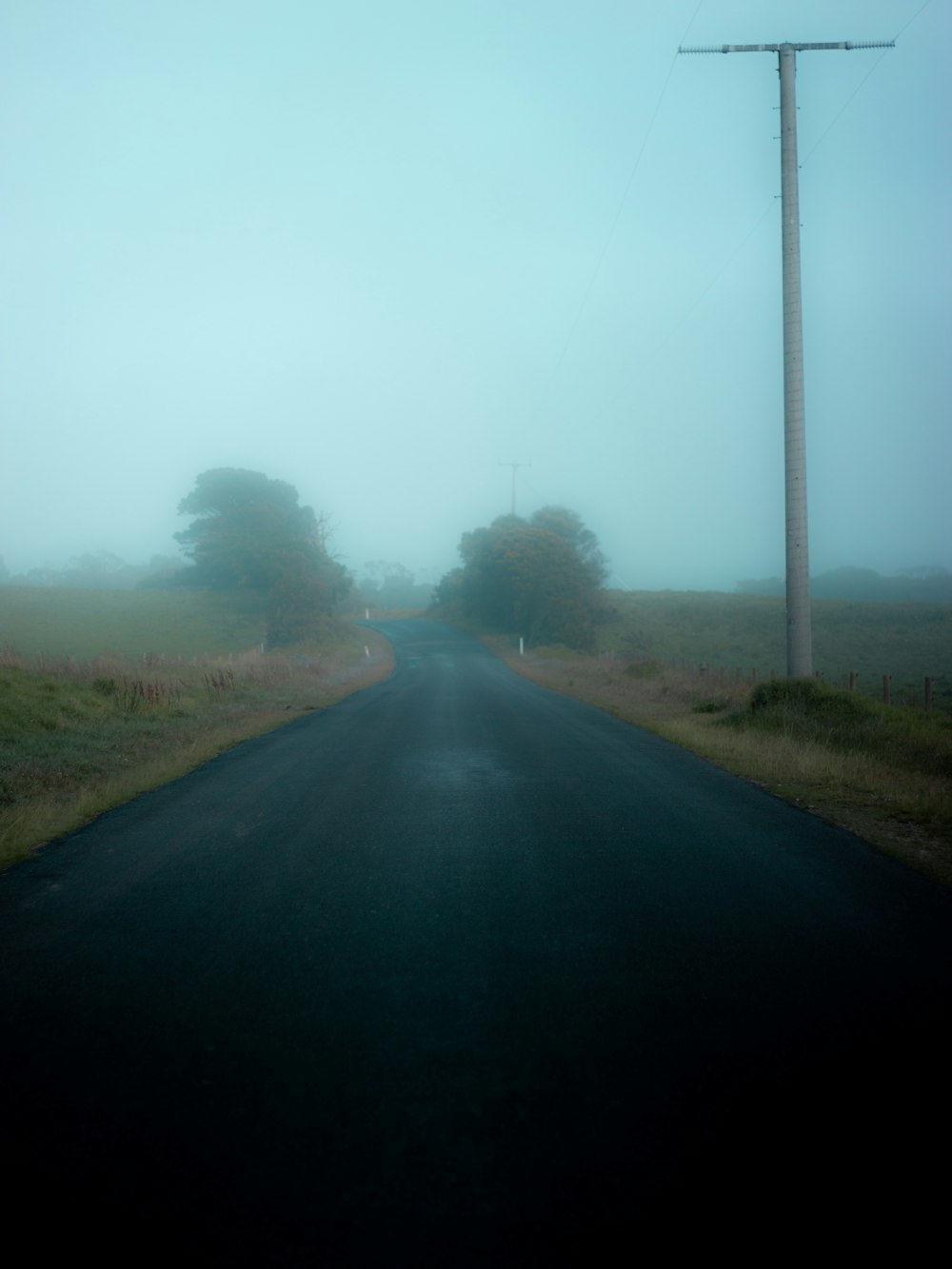 gray asphalt road between green grass field during daytime