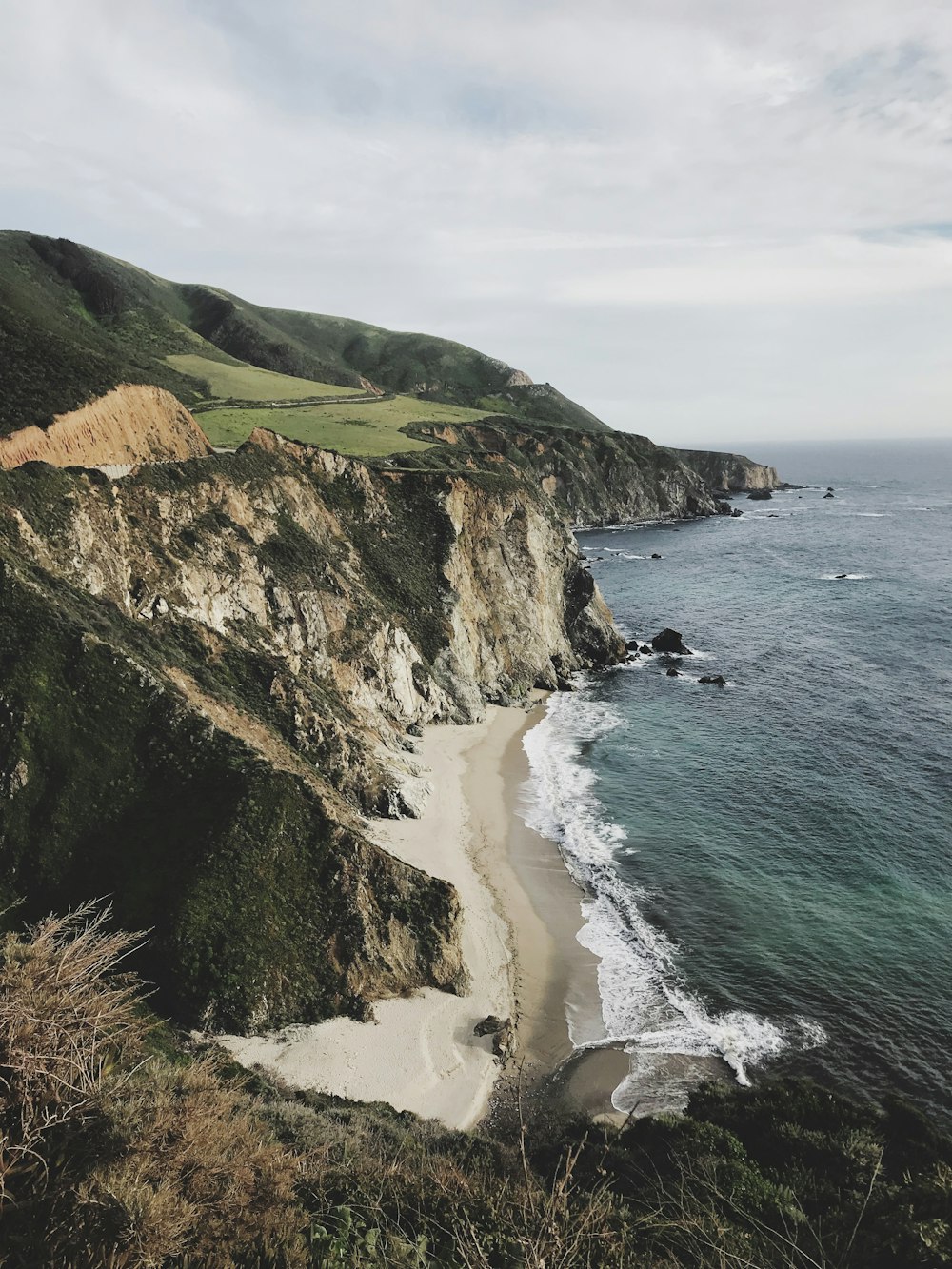 green and brown mountain beside sea during daytime