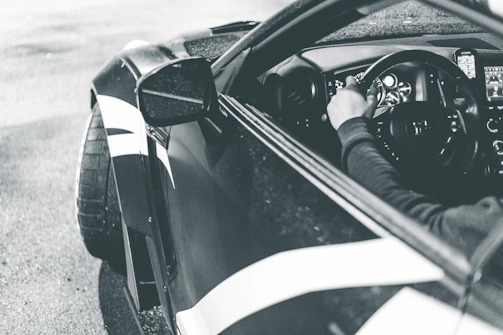 A monochrome shot of a sleek sports car interior with black leather and chrome details.