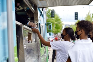 A friendly person at a food truck serving customers.