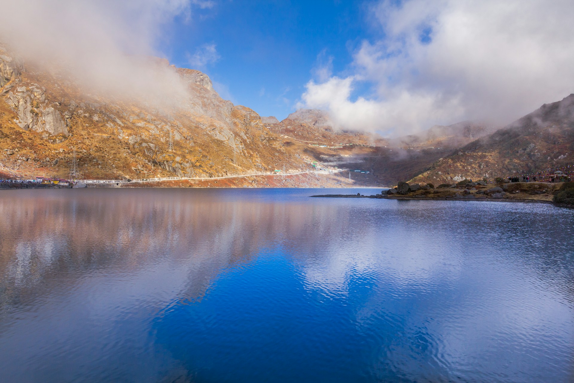 brown and green mountains beside blue lake under blue sky during daytime