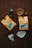 Two packets of Oak & Bond Coffee Co. coffee are placed on a wooden surface with scattered coffee beans. There is a small glass of amber liquid, possibly whiskey or liqueur, next to a dark bottle. A metallic coffee filter holder and a paper filter are also present.