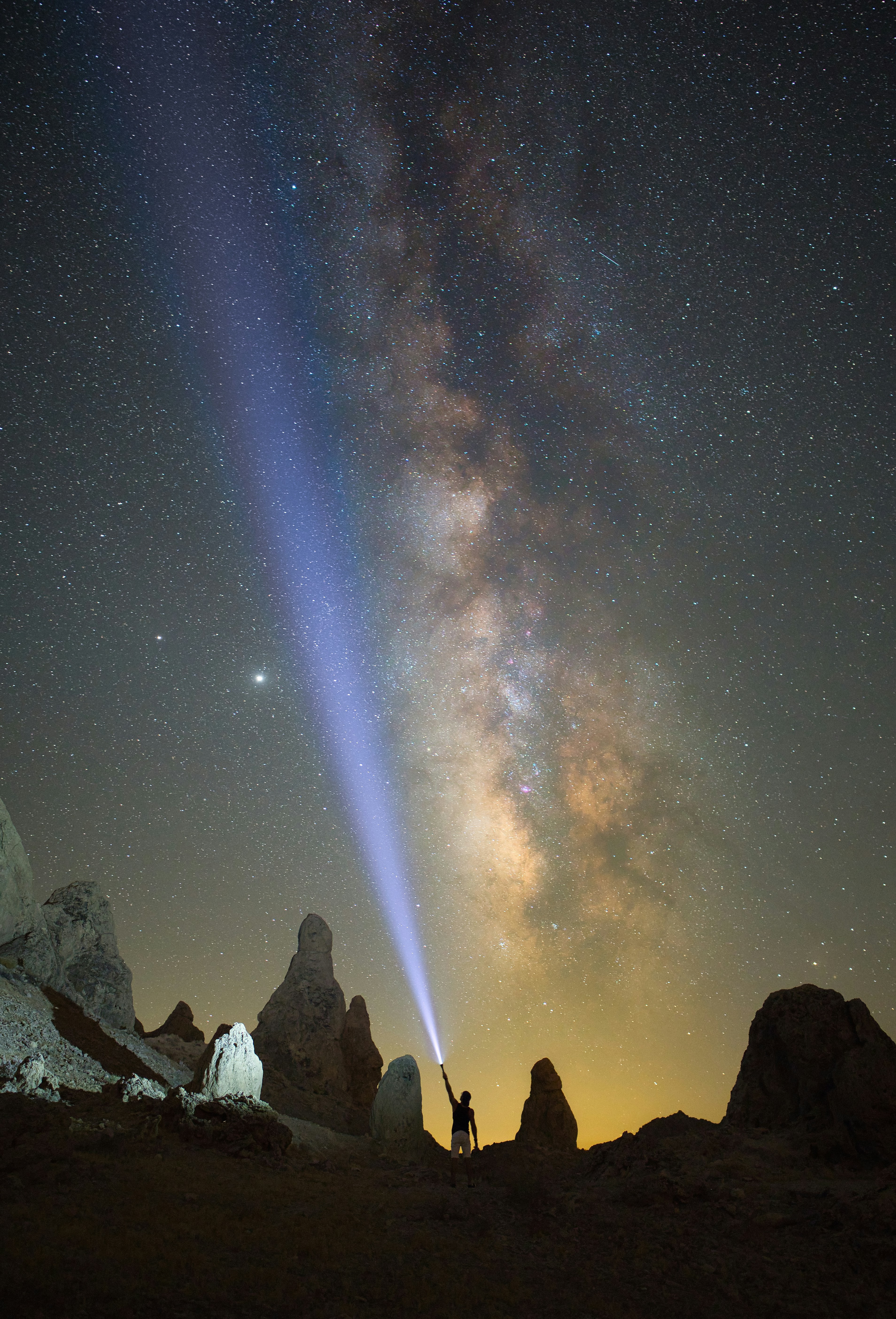Persone in piedi sulla collina rocciosa sotto la notte stellata