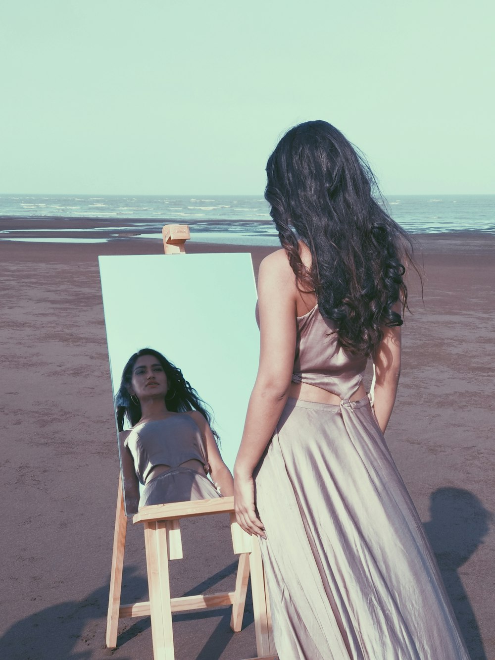 woman in white dress sitting on white wooden chair on beach during daytime