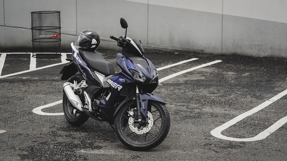 blue and black sports bike parked beside gray concrete wall