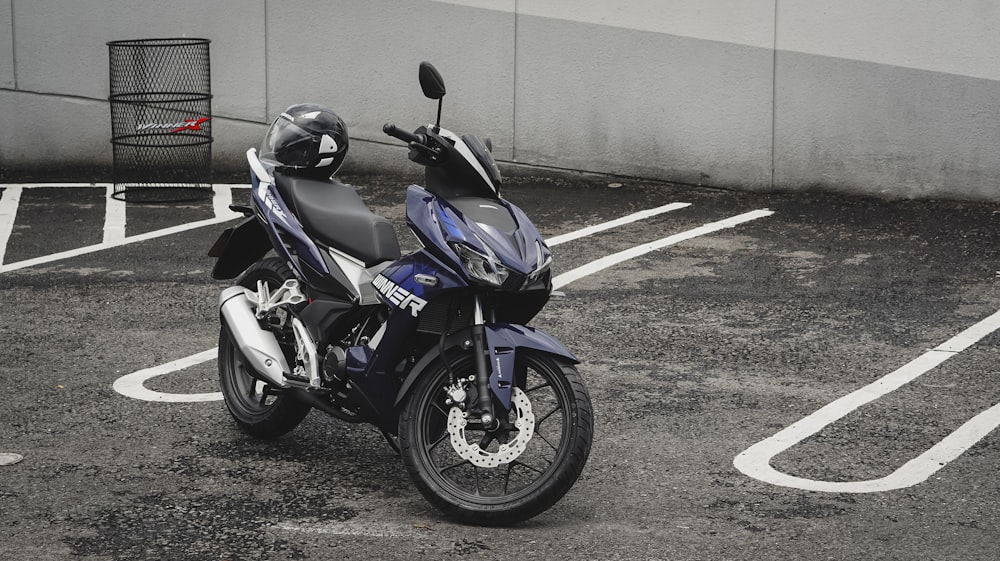 灰色のコンクリートの壁のそばに駐車された青と黒のスポーツバイク