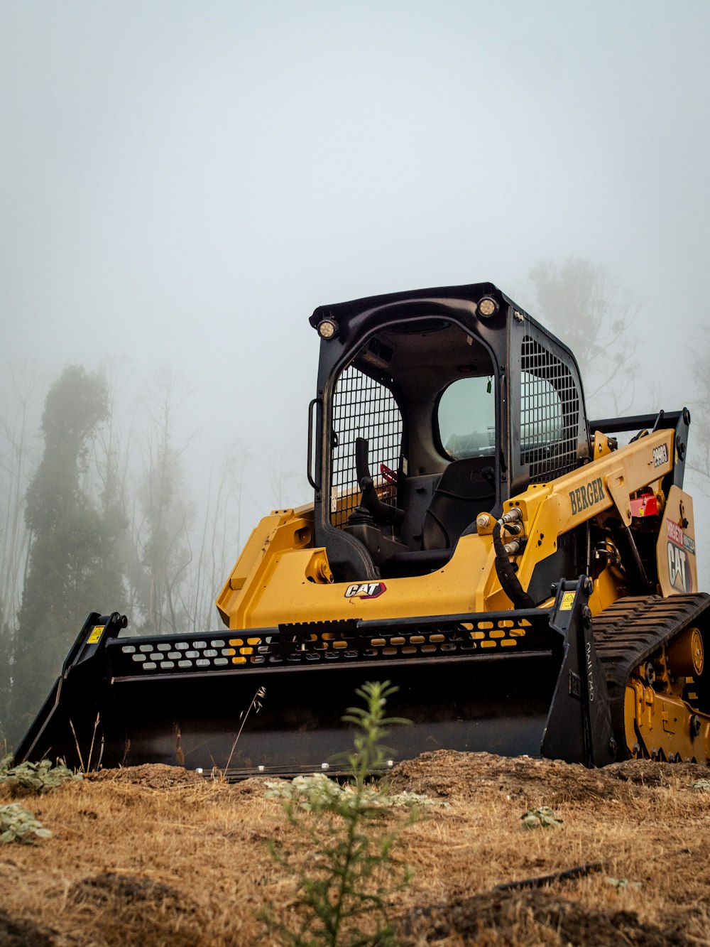 equipamento pesado amarelo e preto no campo de grama marrom