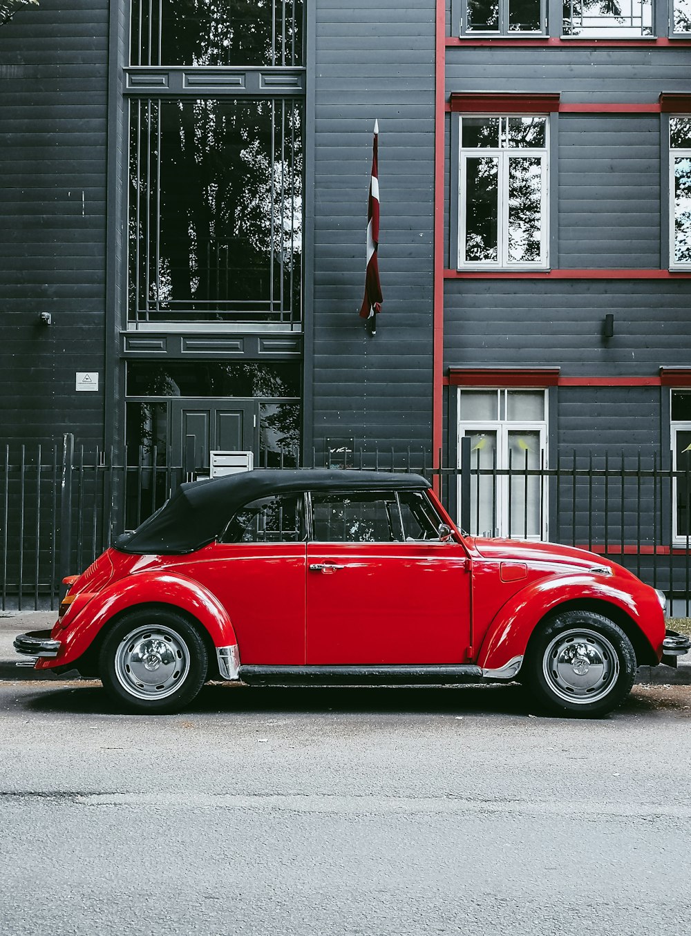 red car parked beside white and gray house