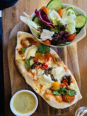 A colorful salad served alongside a slice of Margherita pizza.