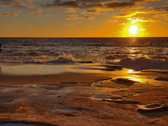 Beautiful Brazilian beach with golden sand and clear blue water at sunset.