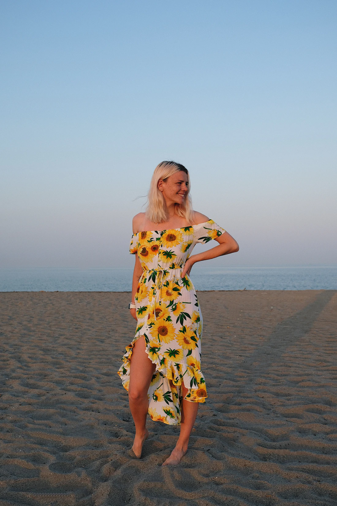 Model in a sunflower print dress on pale sand
