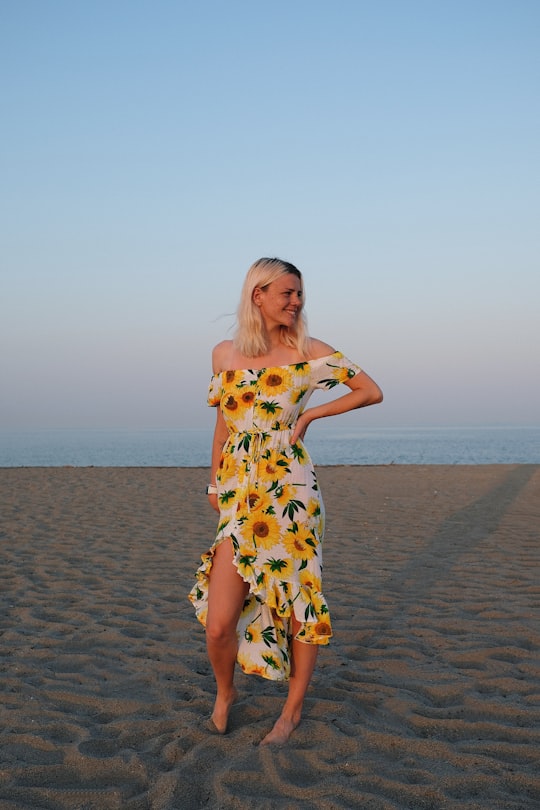 woman in white and yellow floral dress standing on beach during daytime in Sotogrande Spain