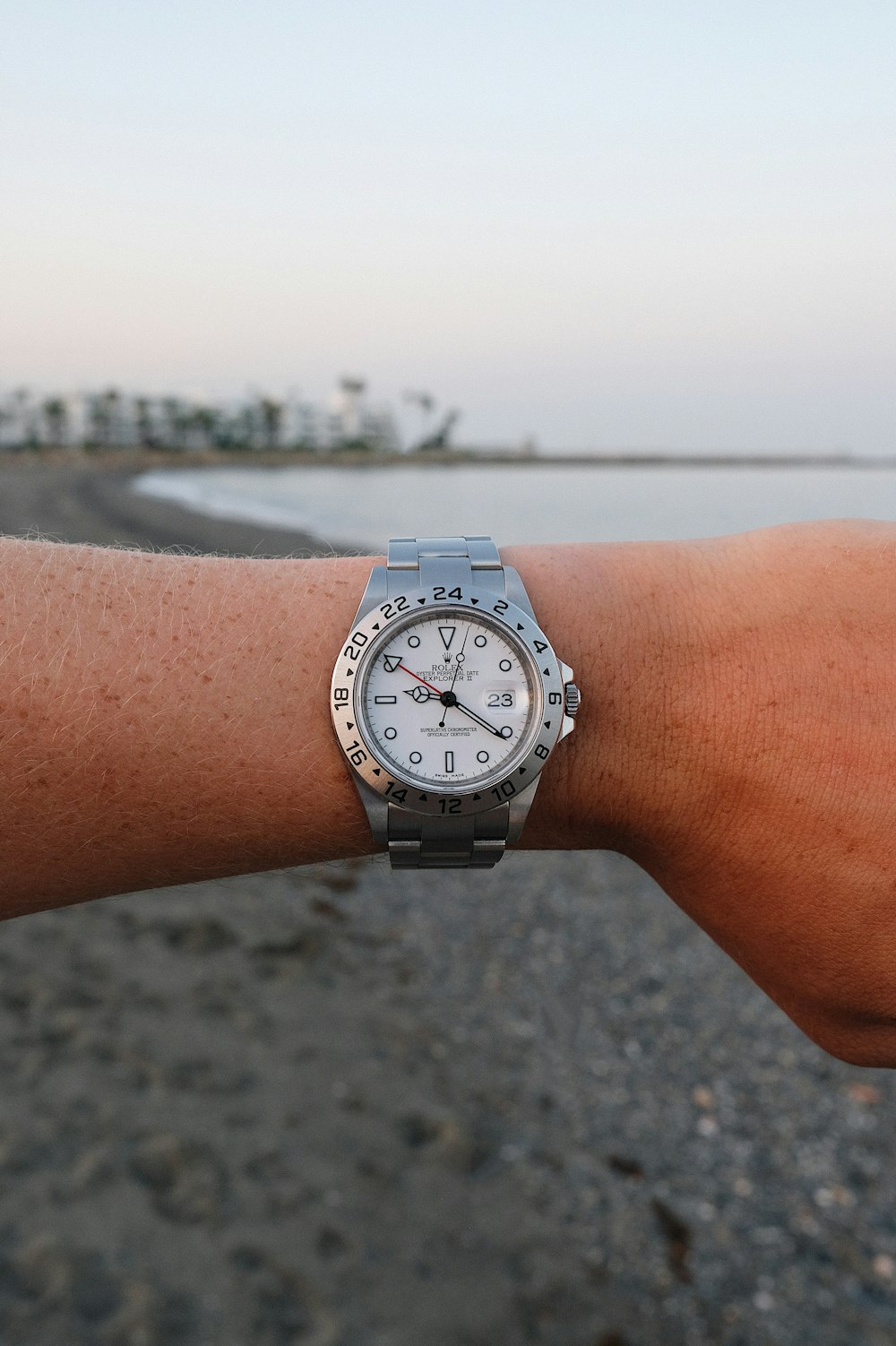 person wearing silver link bracelet round analog watch