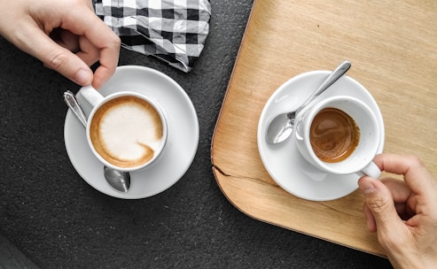 person holding white ceramic mug with brown liquid