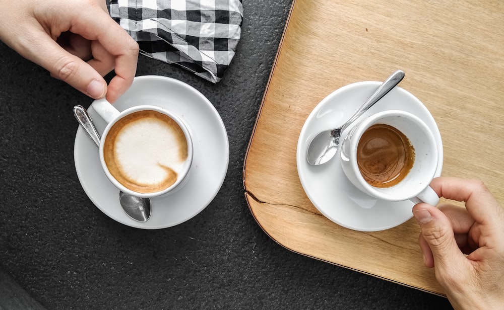 Persona sosteniendo una taza de cerámica blanca con líquido marrón