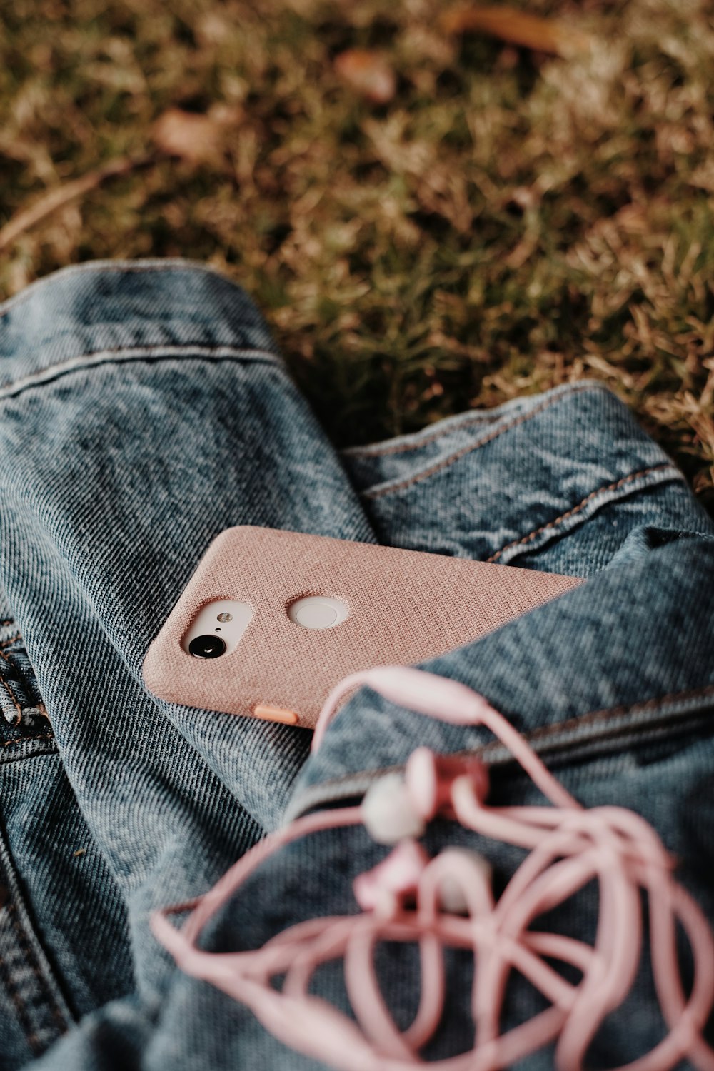 white and red earbuds on blue denim jeans