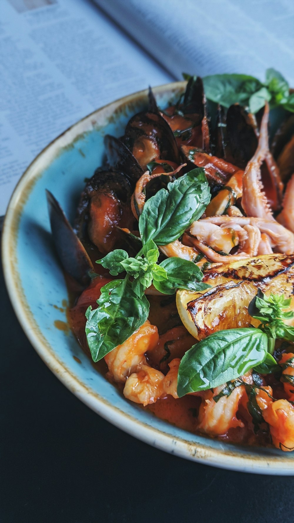 cooked shrimp with green leaf vegetable in blue ceramic bowl