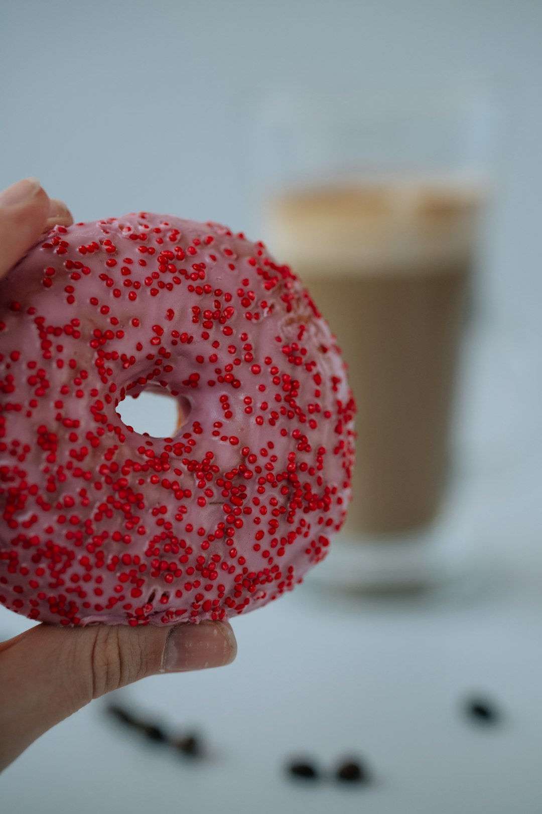 person holding doughnut with red and white sprinkles