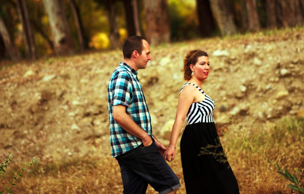 낮에 갈색 잔디밭에 서 있는 남자와 여자