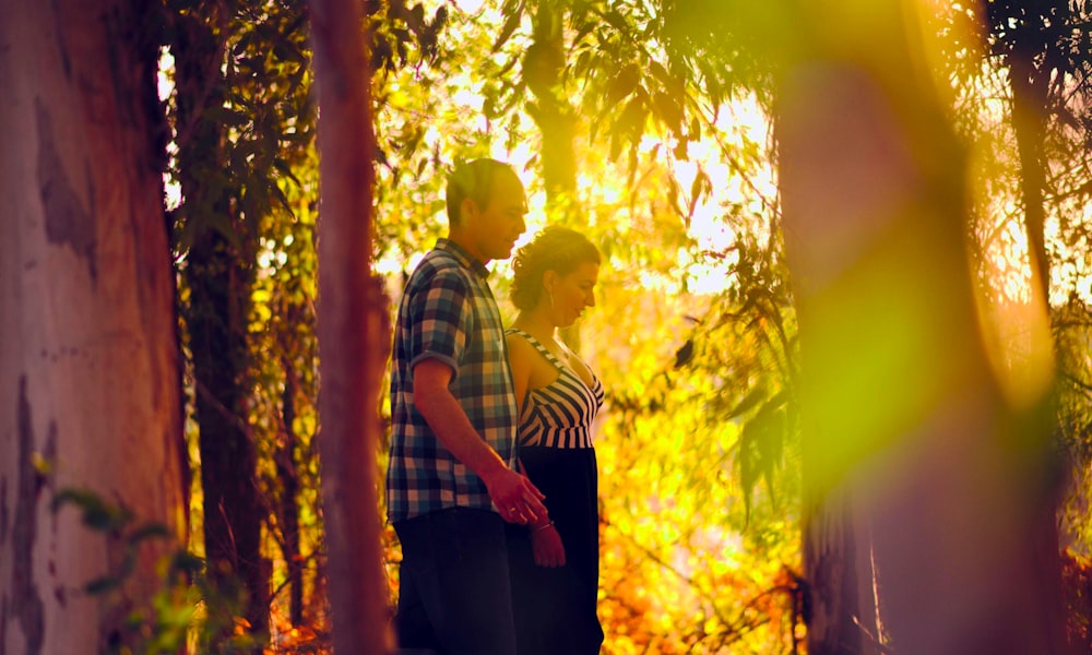 man in black and white striped shirt standing under green tree during daytime