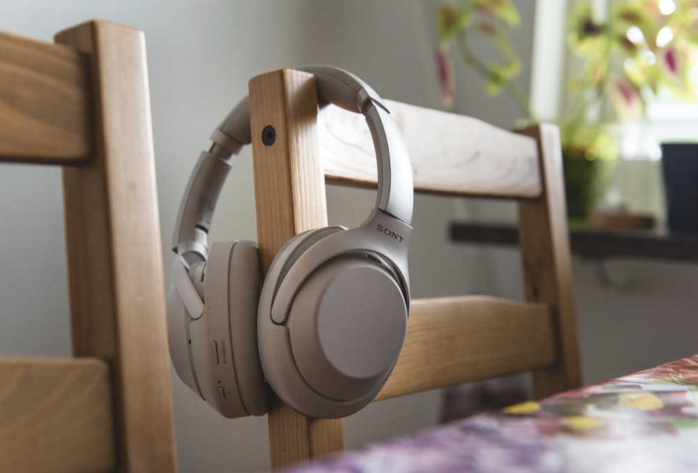white sony headphones on brown wooden chair