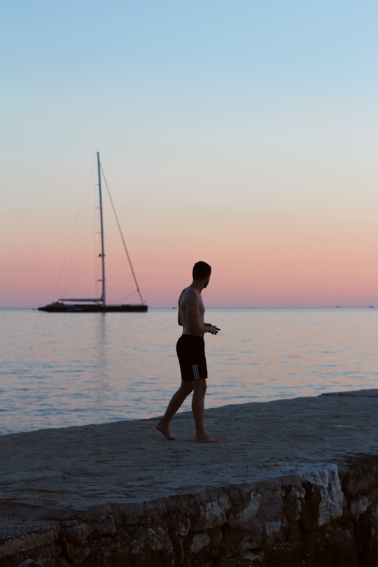 man in black shorts standing on beach during sunset in Rovinj Croatia