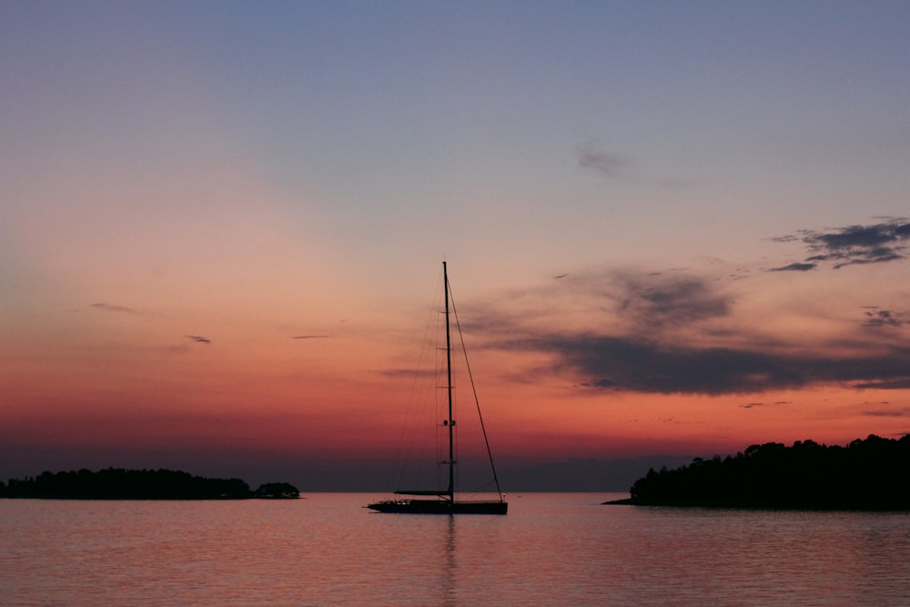 silhouette of boat on sea during sunset