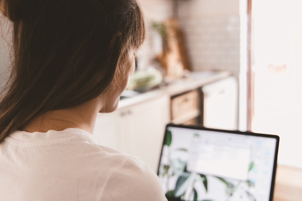 woman in white shirt looking at the computer monitor