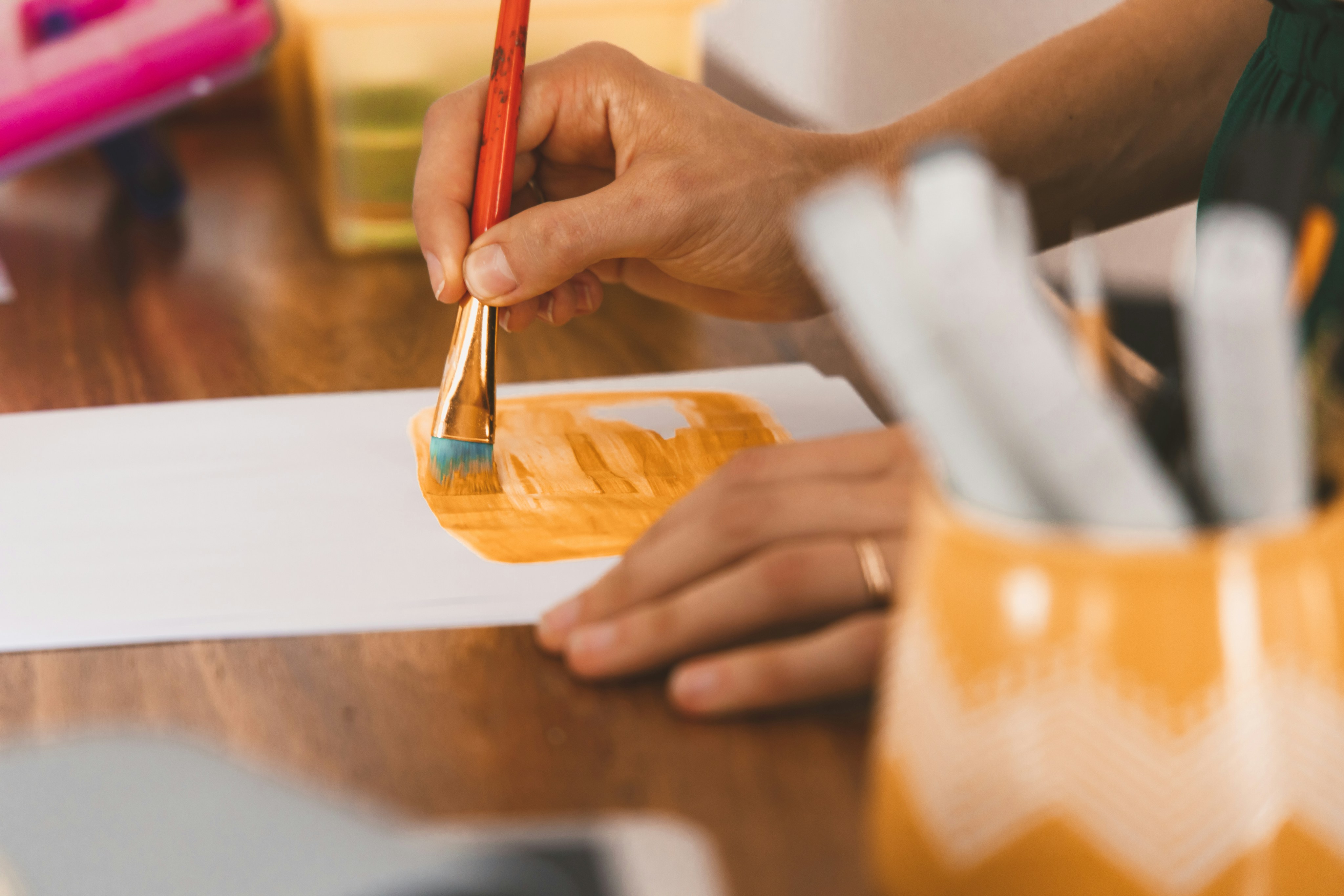 person holding red pen writing on white paper