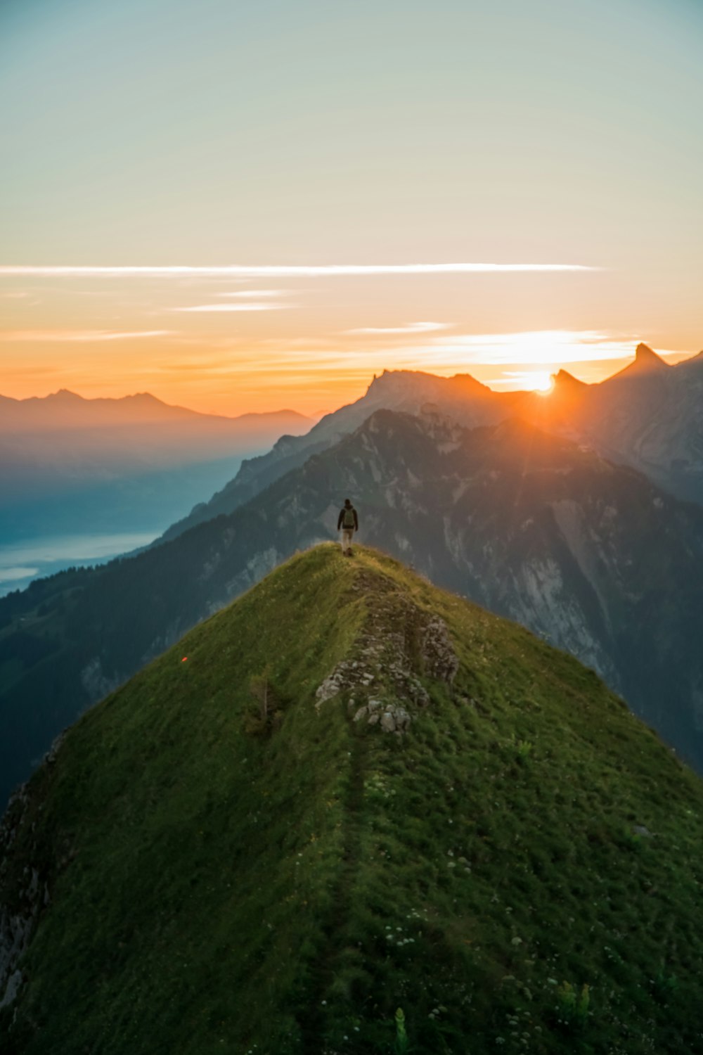 person standing on green mountain during daytime