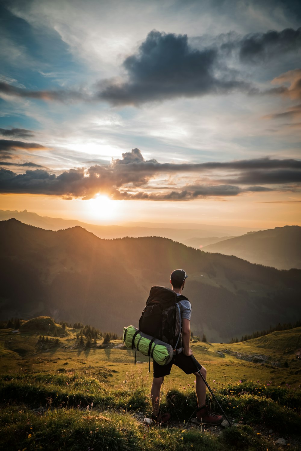 man sitting on green bench looking at the mountains during sunset