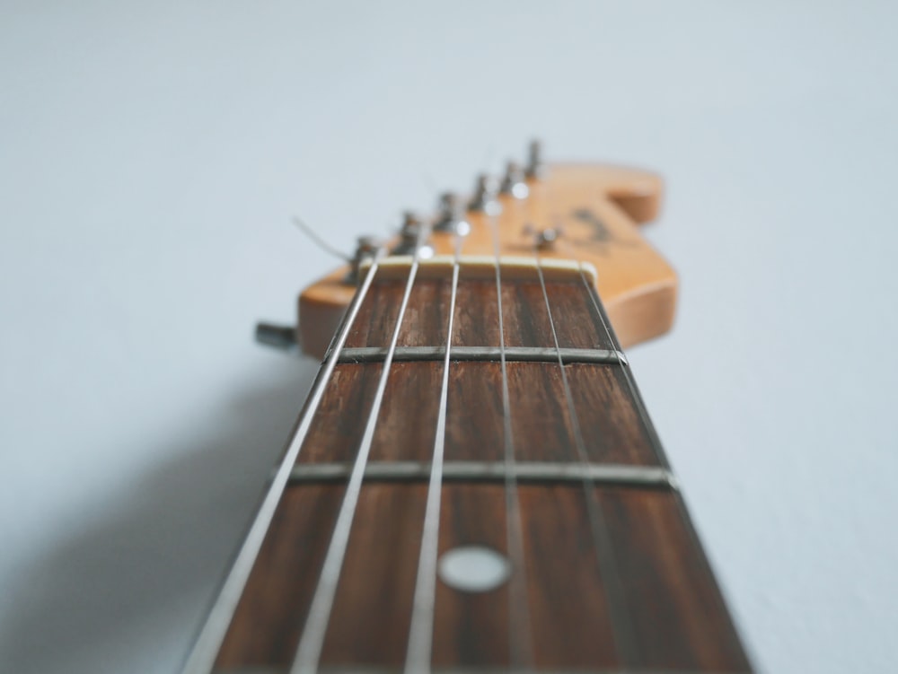 brown acoustic guitar on white wall