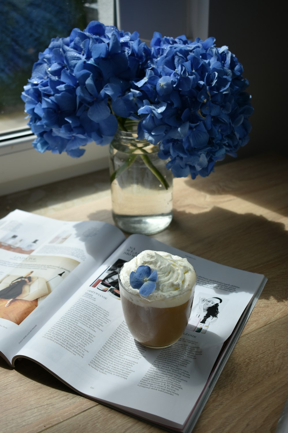 blue flowers in clear glass vase on white paper