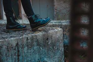 Detail of rugged black boots on cracked concrete with subtle shadows
