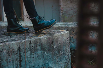 Detail of rugged black boots on cracked concrete with subtle shadows