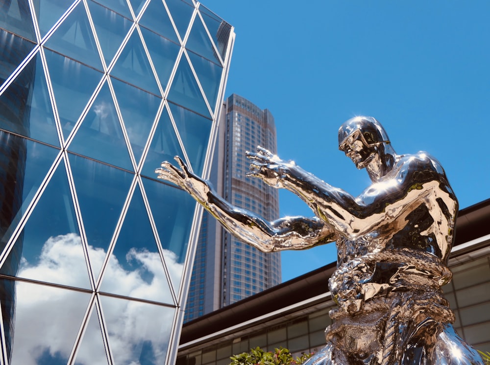man with wings statue near glass building during daytime
