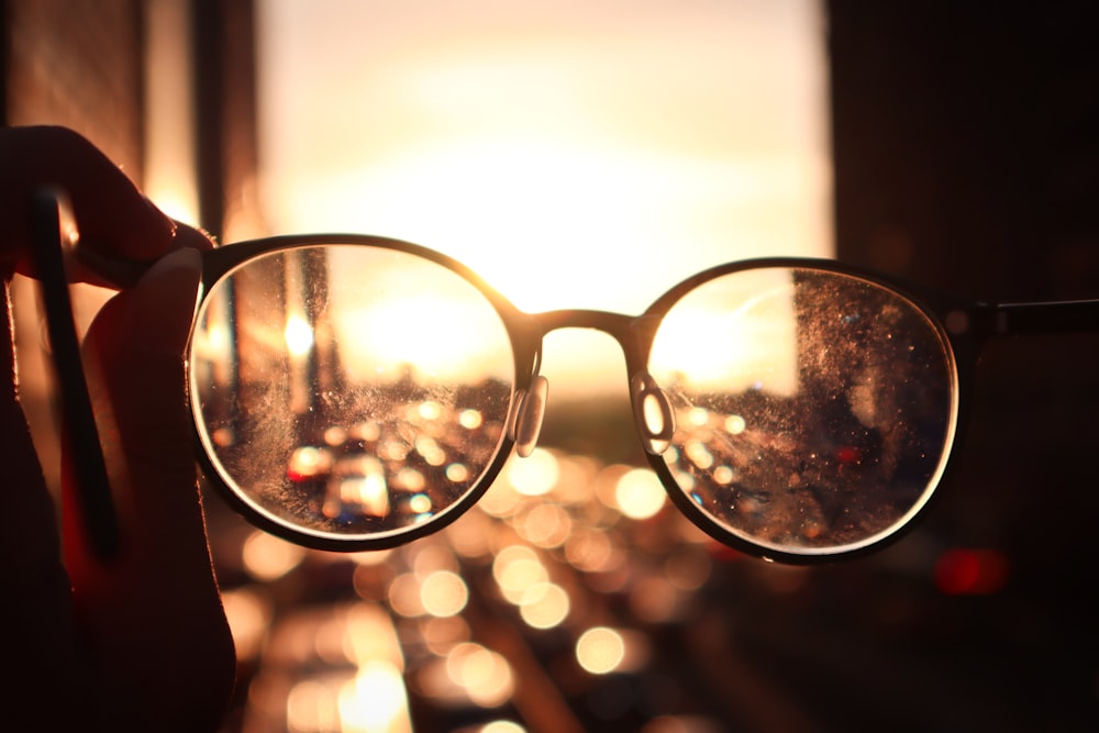 black framed eyeglasses on persons hand