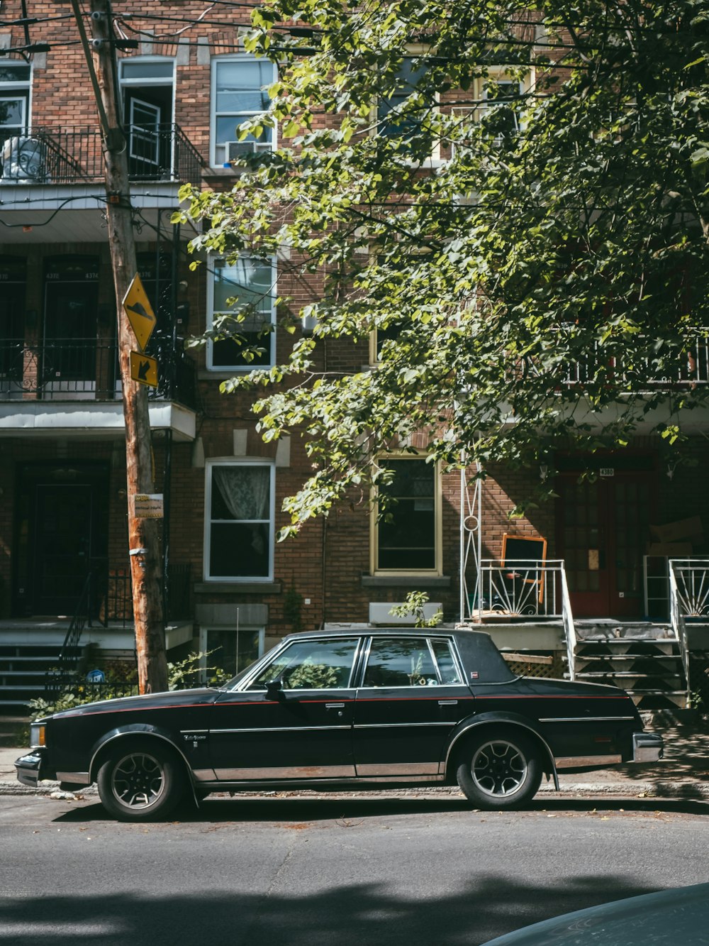 black sedan parked beside brown wooden fence