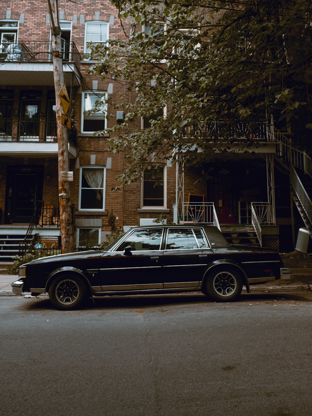 black sedan parked beside brown concrete building during daytime