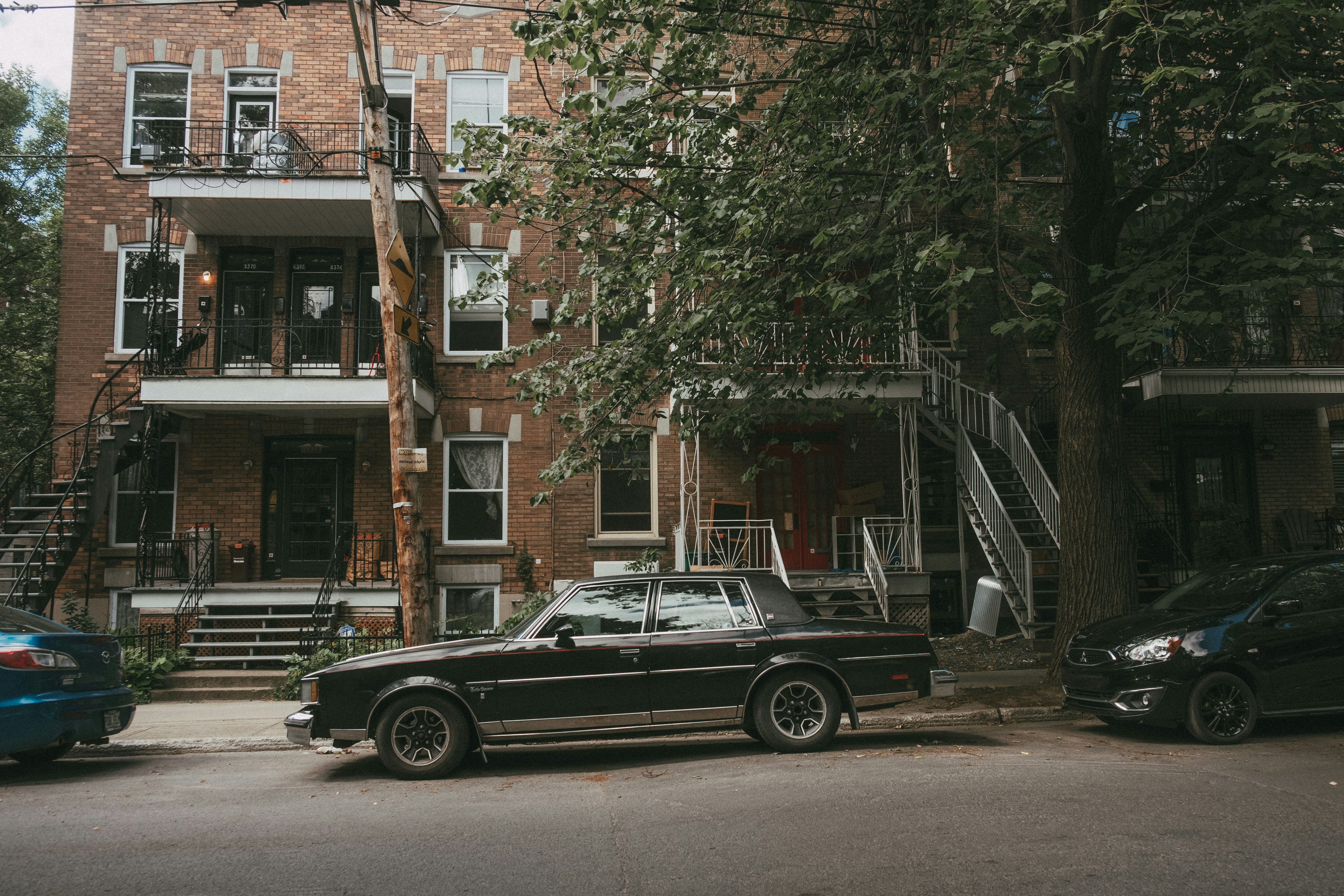 black sedan parked beside brown concrete building during daytime