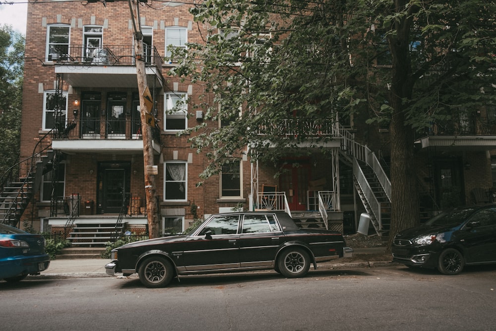 black sedan parked beside brown concrete building during daytime