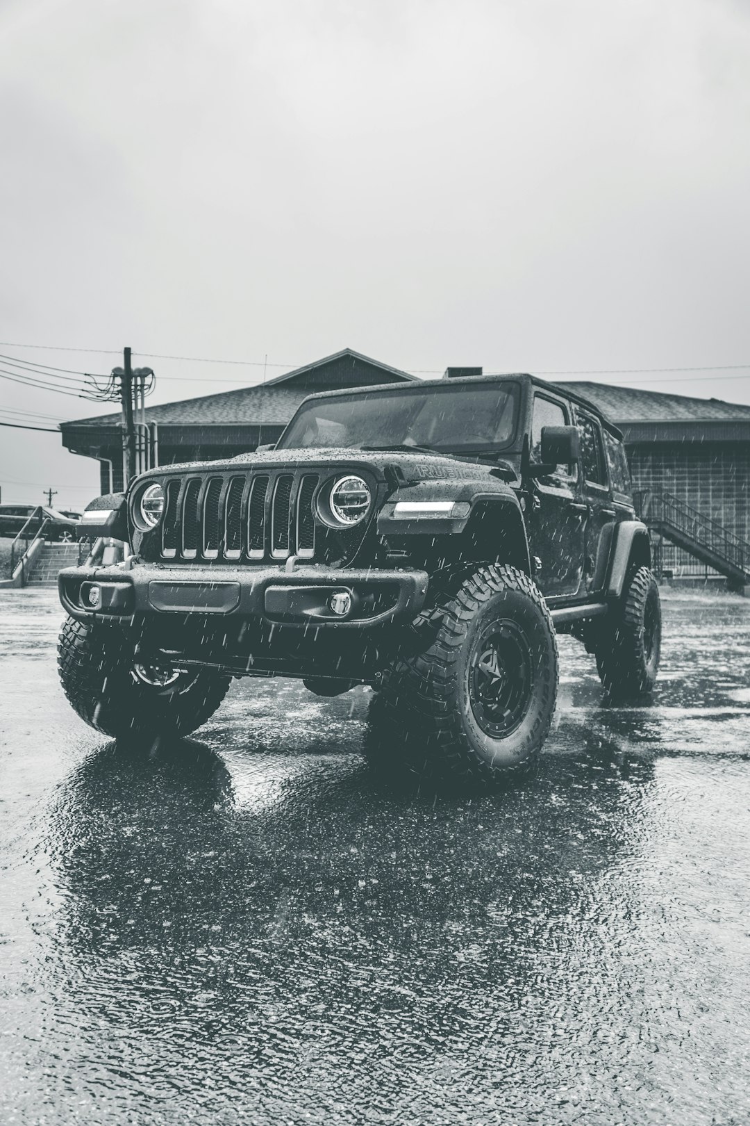 grayscale photo of black jeep wrangler on wet road