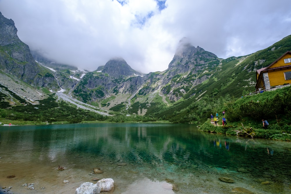 green mountains beside lake under cloudy sky during daytime