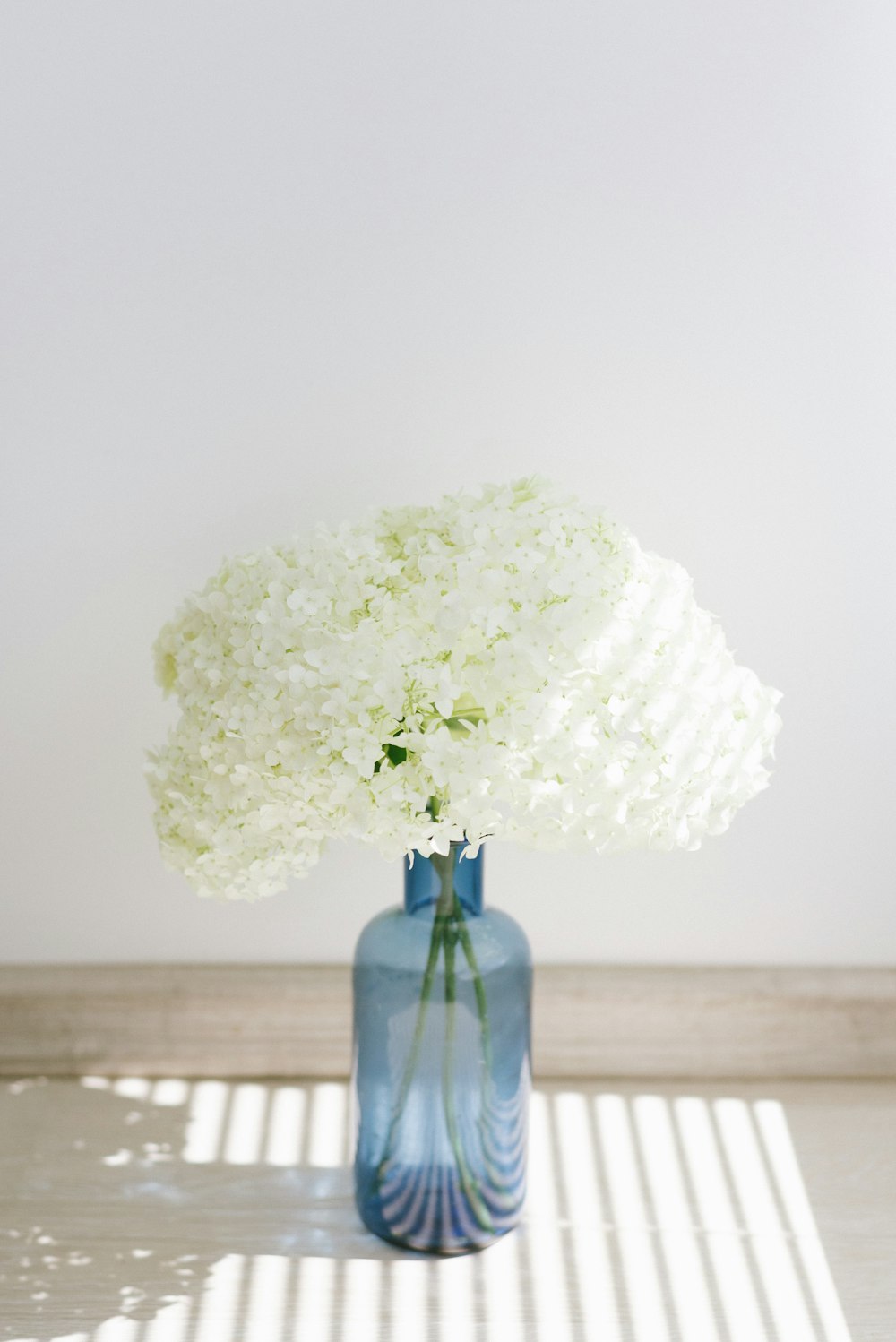 white flower on blue glass vase