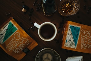 A rustic wooden table displaying an assortment of specialty coffee beans and tasting cups.